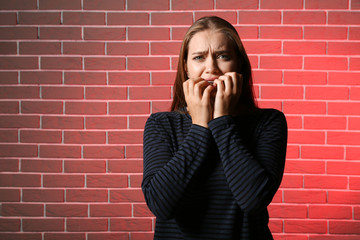 Woman having panic attack against brick wall
