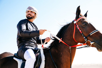Arabian man with traditional clothes riding his horse