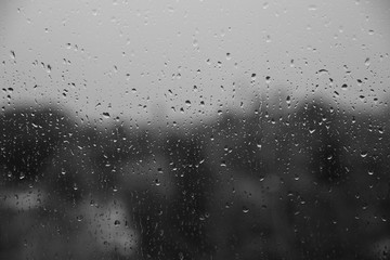 rain drops on window close up, behind gray blurry view, monochrome black and white