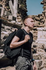 Fototapeta na wymiar Tour of the ancient cities of Turkey.Man at the amphitheater in Side.Young man with big black backpack. Traveler. Holidays in Turkey. Stylish young man