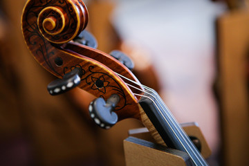 Plakat Details with the scroll, peg box, tuning pegs, strings, neck and fingerboard of a violin before a symphonic classical concert