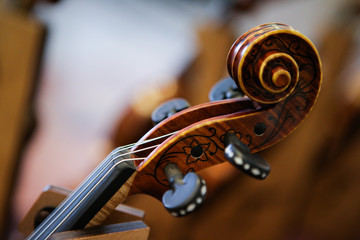 Obraz na płótnie Canvas Details with the scroll, peg box, tuning pegs, strings, neck and fingerboard of a violin before a symphonic classical concert