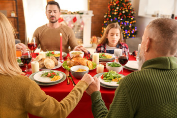 Family praying before having Christmas dinner at home