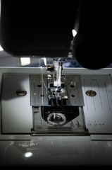 sewing machine foot while working with female hands close
