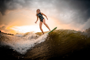 Brunette girl riding on the wakeboard on the river on the wave