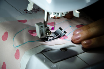 sewing machine foot while working with female hands close