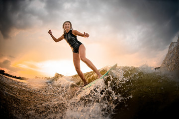 Sporty girl riding on the wakeboard on the river on the wave on the bending knees