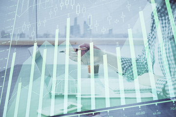 Obraz premium Double exposure of stock market chart with man working on computer on background. Concept of financial analysis.