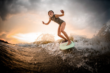 Skinny girl riding on the wakeboard on the river on the wave on the bending knees