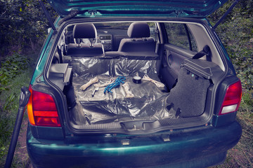Car trunk of killer's vehicle prepared with plastic foil, ropes, tapes and weapons