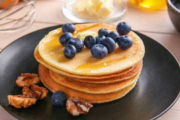 Plate with tasty pancakes on wooden background