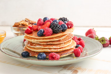 Plate with tasty pancakes and berries on table