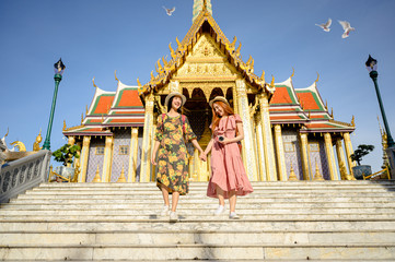 Fototapeta premium young tourist women enjoy trip walking to the palace temple in Bangkok of Thailand, Emerald Buddha Temple, Wat Phra Kaew, Bangkok Royal Palace popular tourist place