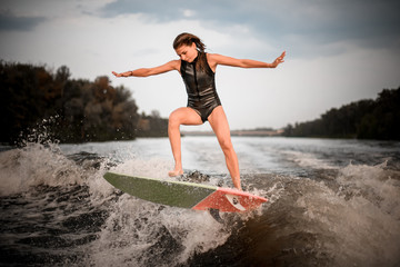 Sporty girl jumping on the wakeboard on the river on the wave