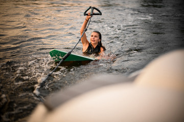 Sporty girl swimming holding the wakeboard and a rope of the motorboat