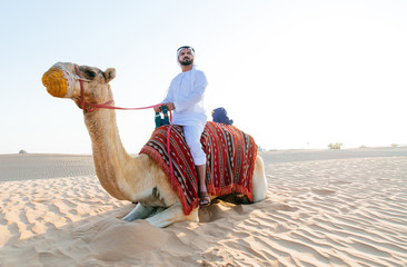 Arabian man with traditional clothes riding his camel