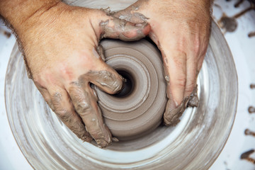 View at an artist makes clay pottery on a spin wheel