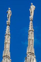 Fototapeta na wymiar Two spires with statues at Milan cathedral in Italy