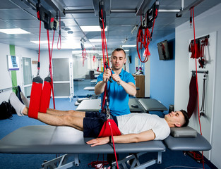 Physiotherapy. Suspension training therapy. Young man doing fitness traction therapy with...