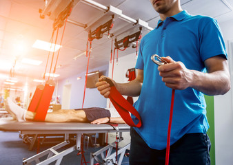 Physiotherapy. Suspension training therapy. Young man doing fitness traction therapy with...