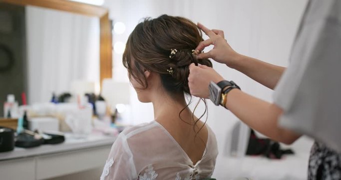 Hairdresser creating a hairstyle for bride in salon