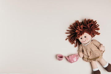 A doll and toy tea set on a white background