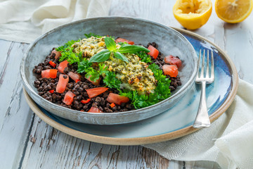 Pesto-crusted cod with Puy lentils and tomatoes in a bowl