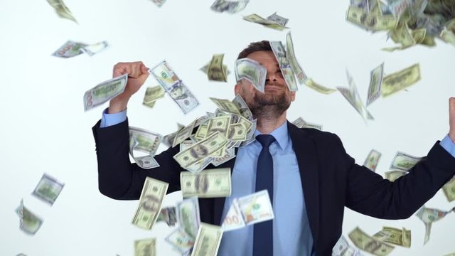 Slow motion of formally dressed man is delighted with the fact that a lot of dollar bills are fall on him