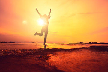 Fototapeta na wymiar silhouette of asian teen woman jump on sunset beach freedom ideas concept