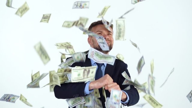 Slow motion of formally dressed man performs a victory dance, and a lot of dollar bills are fall on him