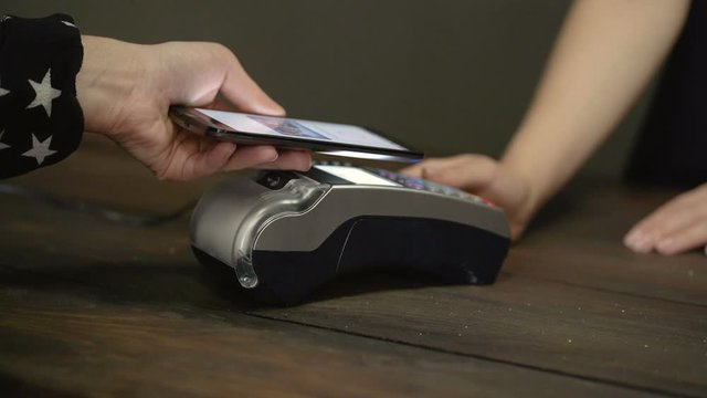 Smartphone payment. Female hand pay using nfc system and contactless card.