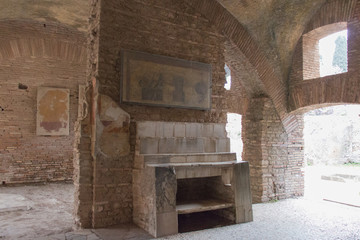 The table and shelves set against the central part of the east wall of room 6 in Ostia Antica,...