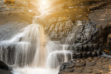 Naklejka premium Waterfall flows through the carved statue