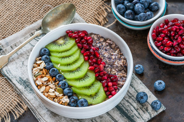 Summer porridge with mixed seeds and fresh fruit - blueberries, pomegranate and kiwi. Healthy breakfast.