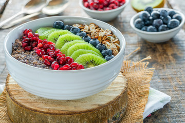 Summer porridge with mixed seeds and fresh fruit - blueberries, pomegranate and kiwi. Healthy breakfast.