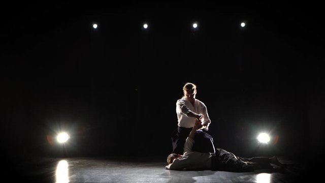 Practicing aikido technique, silhouettes of masters