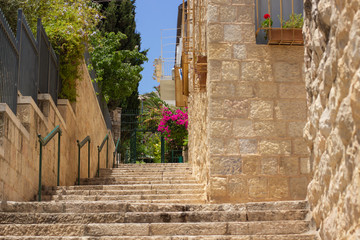 ancient Jerusalem city street narrow stair path way between garden fence and stone buildings without people heritage Israeli touristic destination 