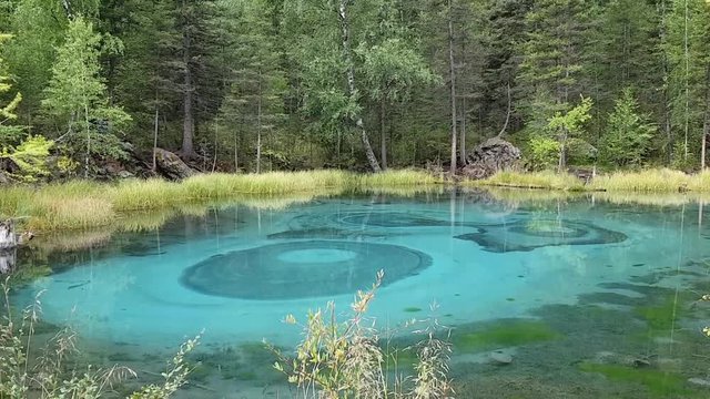 View of the bright lake in the Altai Republic in Russia. Emerald-turquoise color of the water and fancy patterns on the pond.