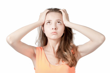 The girl holds her head with his hands on a white background in the studio.