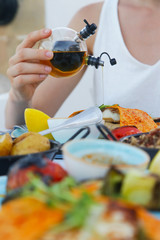 Woman pouring extra virgin olive oil over a meal in the Mediterranean restaurant
