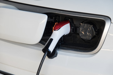 Close up charging an electric car battery. Electric car at charging station with the power cable supply plugged in