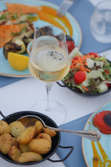 A glass of white wine and various food on the table