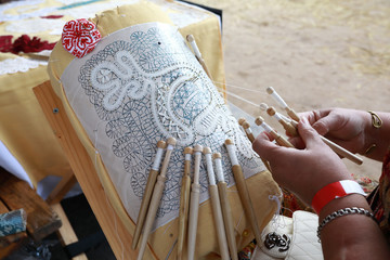 Woman weaves lace with bobbins