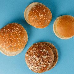 Rye and classic bun empty isolated. American food classic rye round burger bread isolated on a blue background. Four different fried hamburger bun tops.