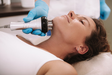 Cropped shot of a woman getting skin tightening treatment on her neck and chin. Beautician doing rf-lifting facial procedure on female client
