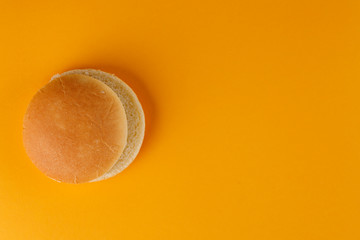 Burger bun empty isolated. American food classic round burger bread isolated on a orange background. Grilled burger bun top.