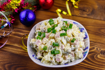 Traditional Russian festive salad Olivier and New Years decorations on wooden table