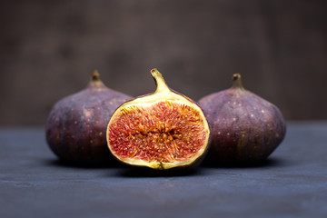 Three whole ripe purple figs on wooden background. Healthy food. Copy space.