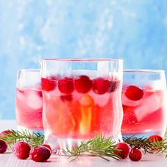 Winter non alcoholic cocktail with cranberry and ice on bright blue background, closeup