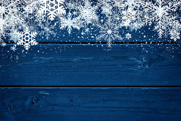 Blue Christmas winter background with snowflakes on wood